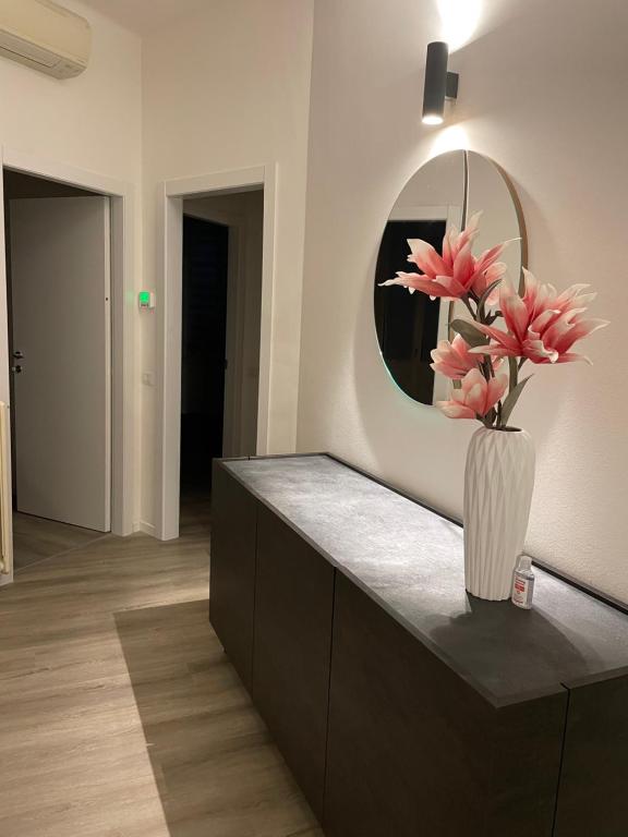 a vase with pink flowers on a counter with a mirror at Un balcone sul centro storico in Reggio Emilia