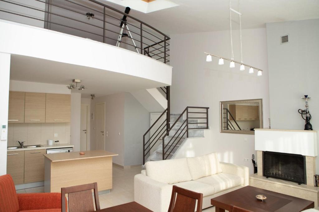una sala de estar con muebles blancos y una escalera. en Οροφομεζονέτα σε συγκρότημα κατοικιών-Μοναδική θέα, en Polígiros