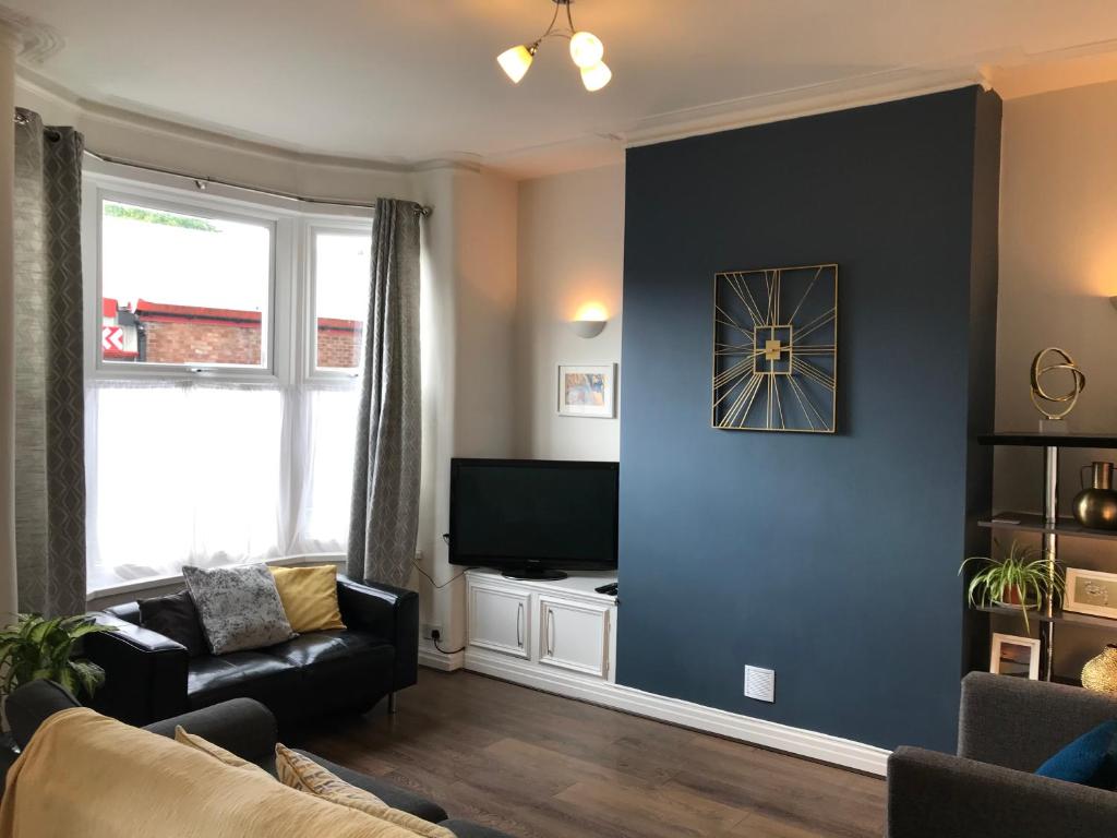 ein Wohnzimmer mit einem Sofa und einem TV an der Wand in der Unterkunft 3 bedroom house in Preston close to M6 & M55 in Preston