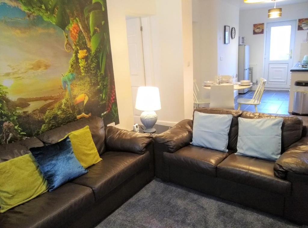 a living room with two brown leather couches with colorful pillows at Modern comfy 2-Bedroom flat in St Helens in Saint Helens