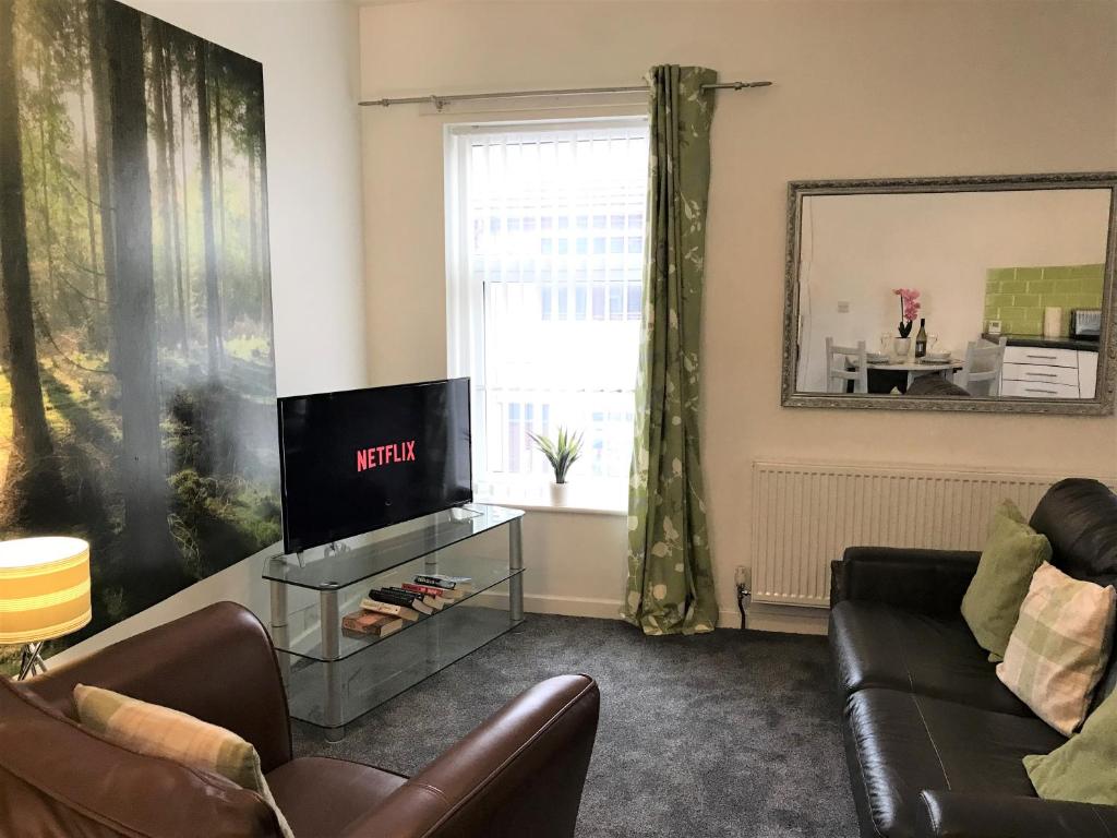 a living room with a couch and a tv at Restful 1-Bedroom flat in St Helens in Saint Helens