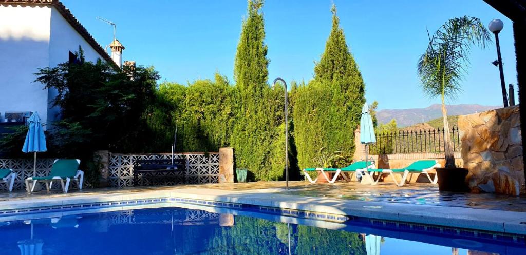 una piscina con sillas, mesas y árboles en Hotel Rural Los Jarales en Istán