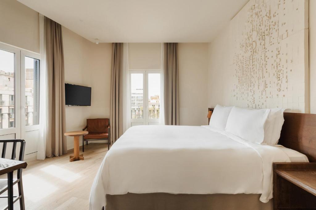 a hotel room with a bed, chair, and window at Sonder Casa Luz in Barcelona