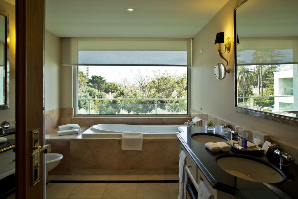 a bathroom with two sinks and a tub and a window at Hotel Cascais Miragem Health & Spa in Cascais