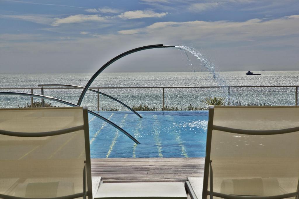 a swimming pool with two chairs and a fountain at Hotel Cascais Miragem Health & Spa in Cascais