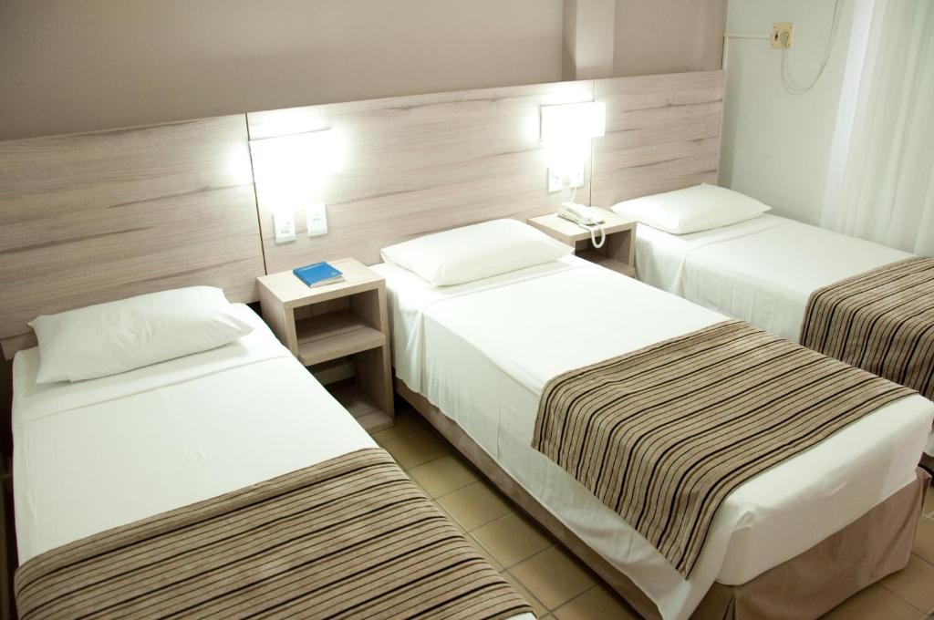 a hotel room with two beds and two tables at Hotel Linhatur in Linhares