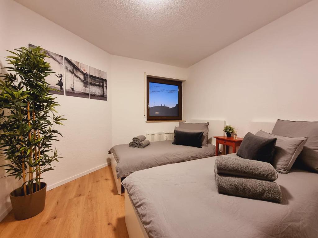 a bedroom with two beds and a potted plant at Lifestyle-Appartment near BASF in Ludwigshafen in Ludwigshafen am Rhein