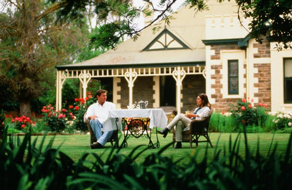 a man and woman sitting at a table in front of a house at The Lodge Country House in Marananga