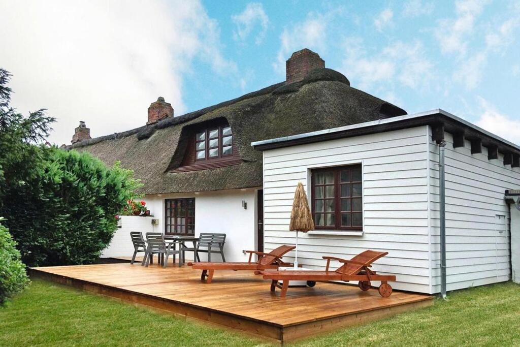 eine Terrasse mit zwei Bänken und einem strohgedeckten Haus in der Unterkunft Terraced house, Hedwigenkoog in Hedwigenkoog