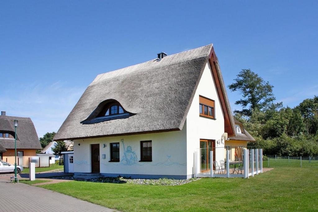 uma casa branca com telhado de palha em Ferienhaus Poseidon mit Meerblick am Breetzer Bodden in Vieregge em Vieregge