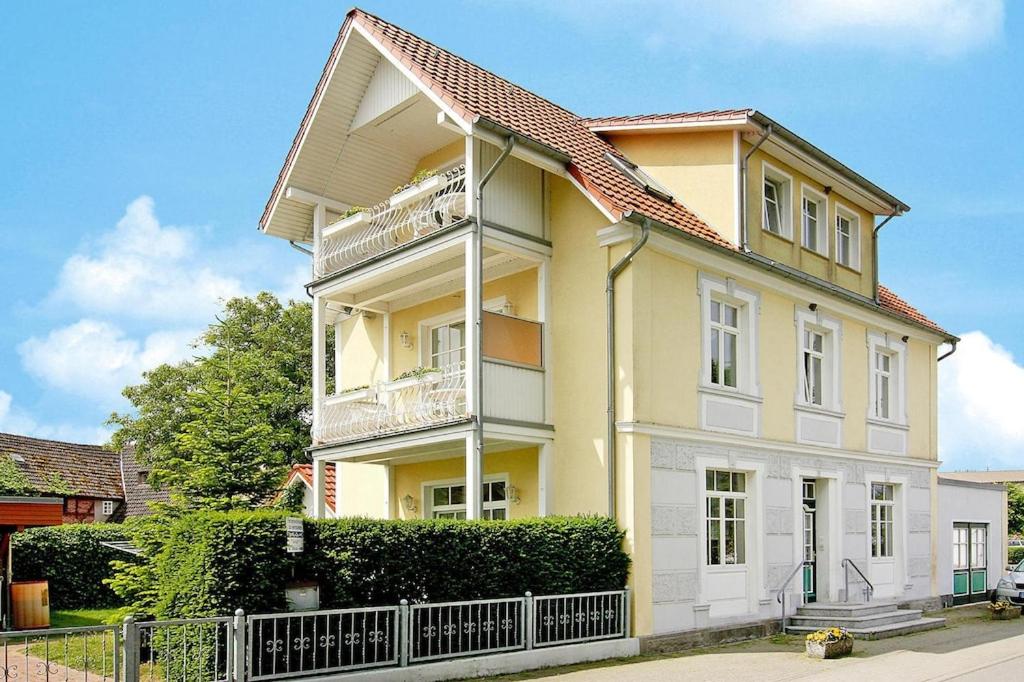 una casa amarilla y blanca con una valla en Apartments Jeske Altenkirchen, en Altenkirchen