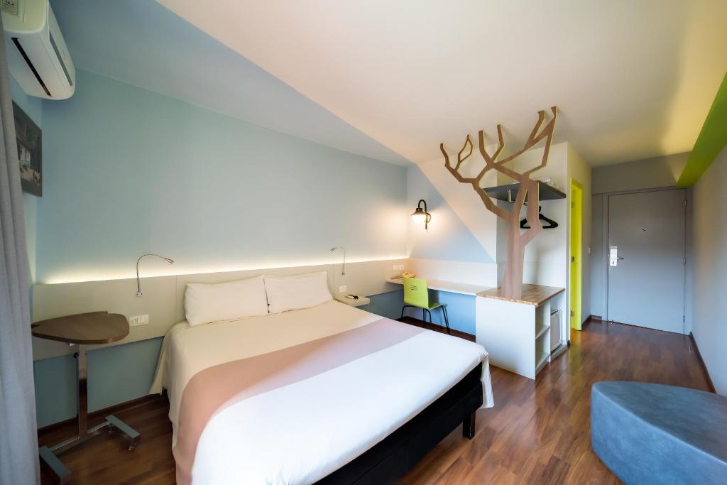 um quarto com uma grande cama branca e uma secretária em ibis Styles Curitiba Centro Civico em Curitiba