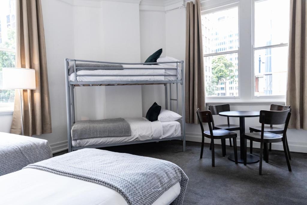 a bedroom with two bunk beds and a table and chairs at Wynyard Hotel in Sydney