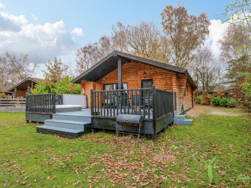 eine Blockhütte mit einer Veranda und einer Terrasse in der Unterkunft Sunset Lodge in Tattershall