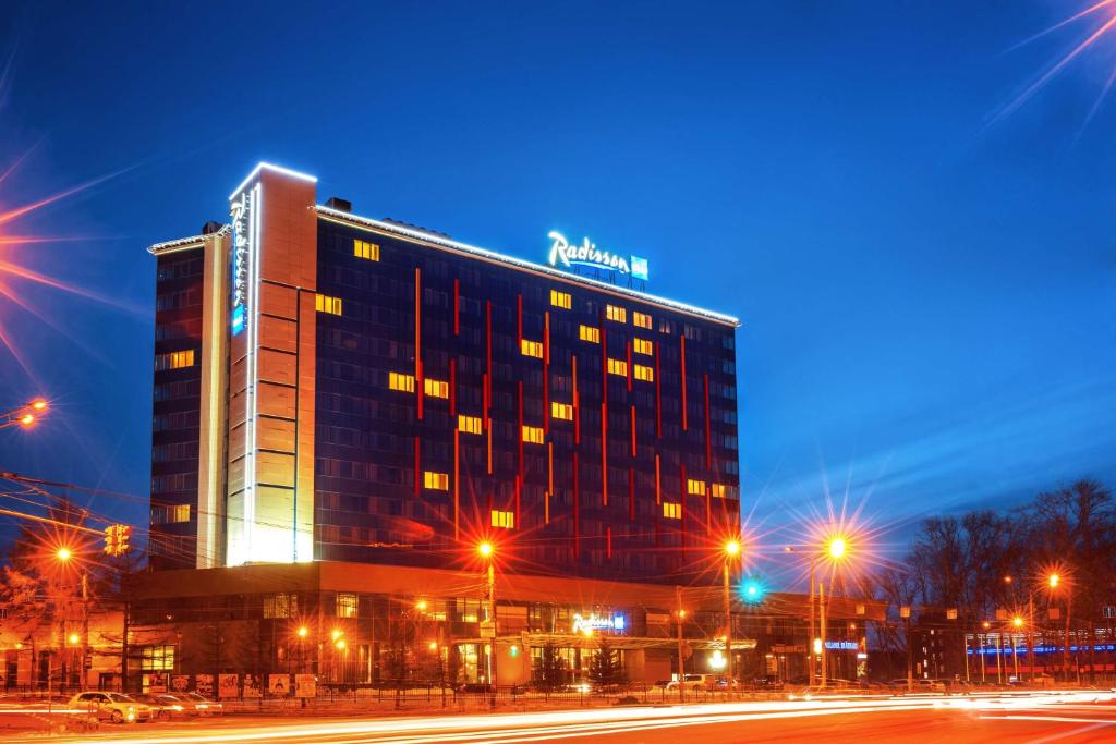 a building with a sign on top of it at night at Radisson Blu Chelyabinsk Hotel in Chelyabinsk