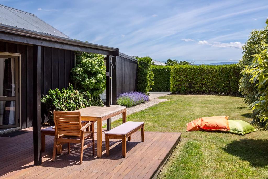 a garden with a wooden table and chairs on a deck at The Escape in Martinborough