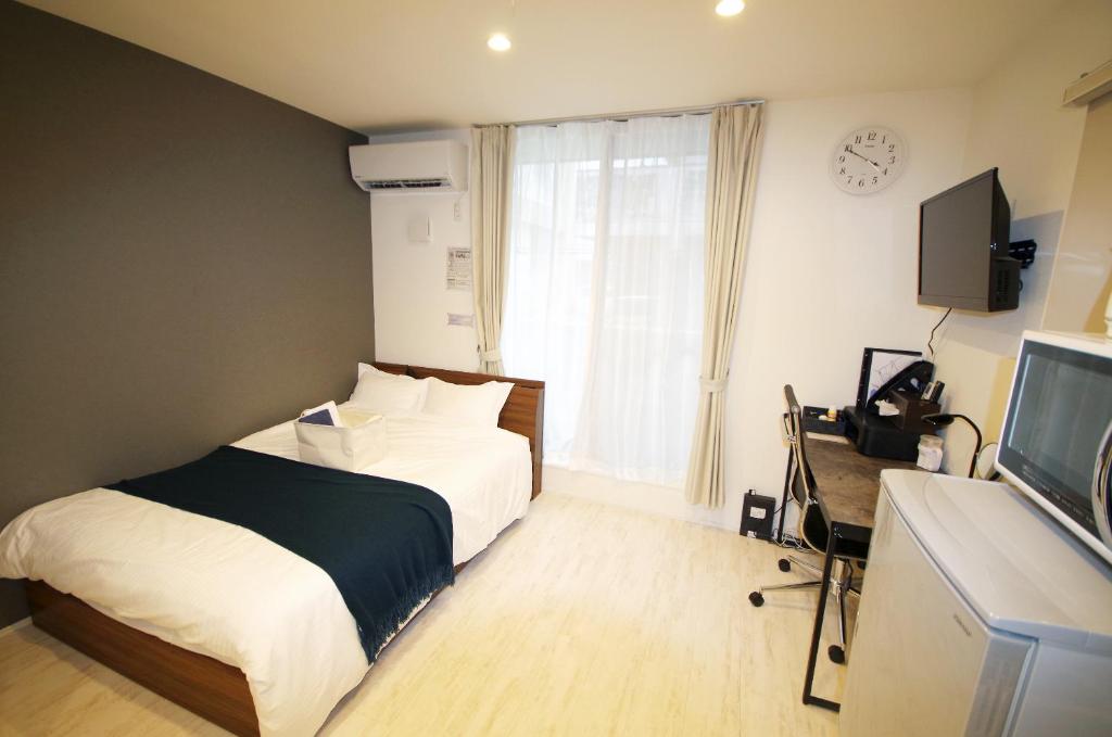1 dormitorio con 1 cama, TV y ventana en ラ・ルーチェ東仲宗根, en Isla Miyako
