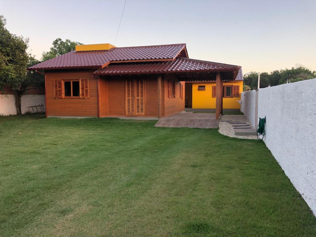 uma pequena casa com um relvado verde em frente em Casa em Ibiraquera próxima a praia do Rosa em Imbituba