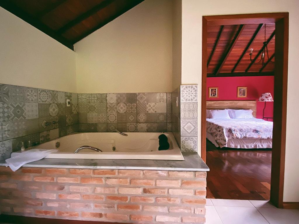 a bath tub in a room with a bedroom at Chalés da Estrada Velha in Tiradentes