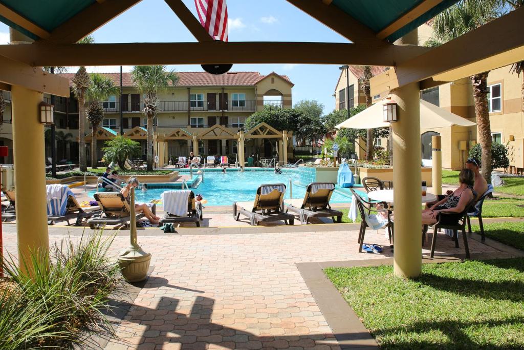 personnes assises sur des chaises au bord de la piscine d'un complexe dans l'établissement Gorgeous Condo Near Disney, à Orlando