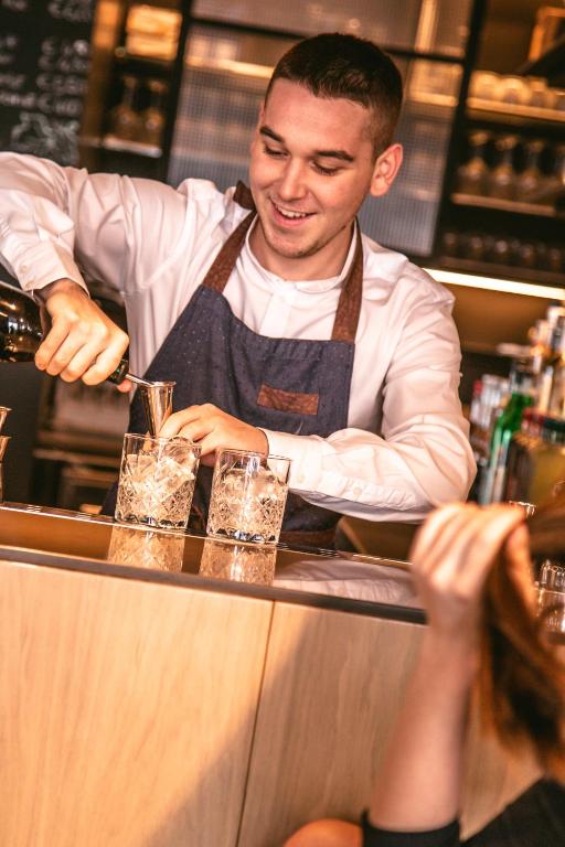 a man bartender making drinks at a bar at Mosella Suite Hotel in Sottomarina