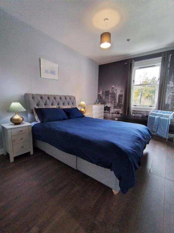 a bedroom with a large bed with a blue blanket at Modern and Spacious flat near Edinburgh in Prestonpans