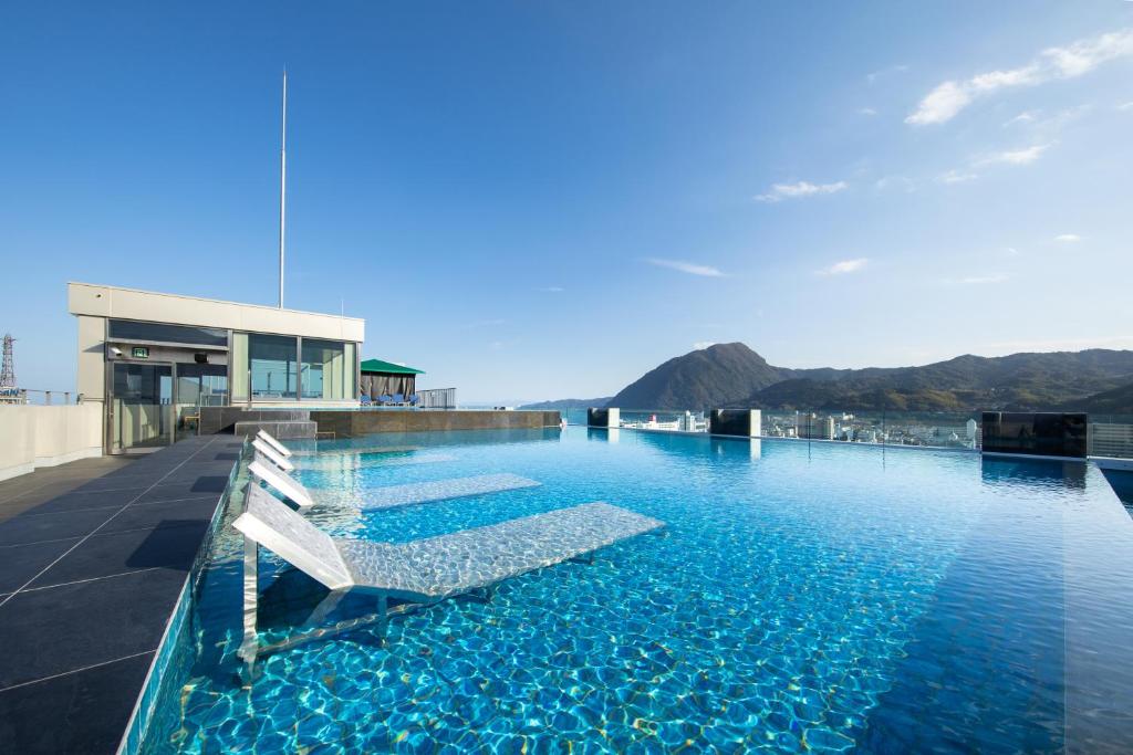 a swimming pool with chairs on the roof of a building at AMANEK Beppu YULA-RE in Beppu