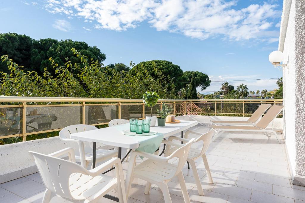 um pátio com mesas brancas e cadeiras brancas em Villa 30 m from the beach Cambrils em Cambrils