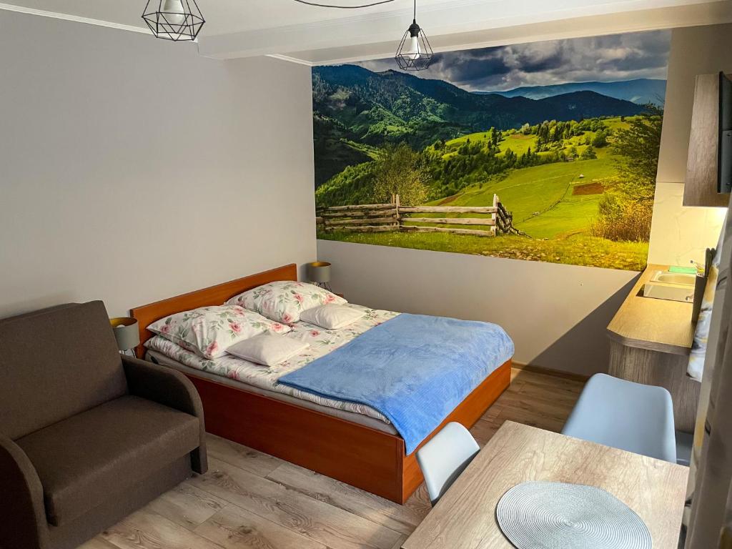 a bedroom with a bed and a chair and a painting on the wall at Pokoje Beata in Wisła