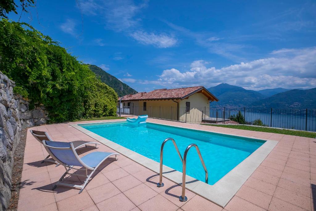 a swimming pool with two chairs and a house at Parco dei Cervi Terrazzo in Menaggio