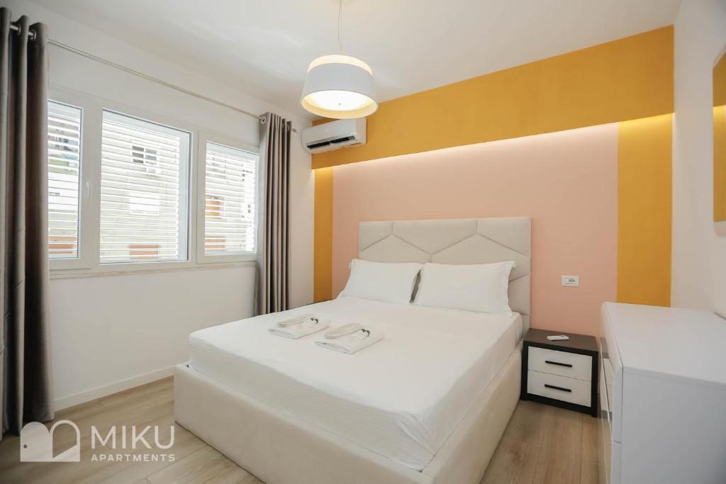 ein Schlafzimmer mit einem weißen Bett und einer gelben Wand in der Unterkunft Miku Apartment-Brand New at Wilson Square in Tirana