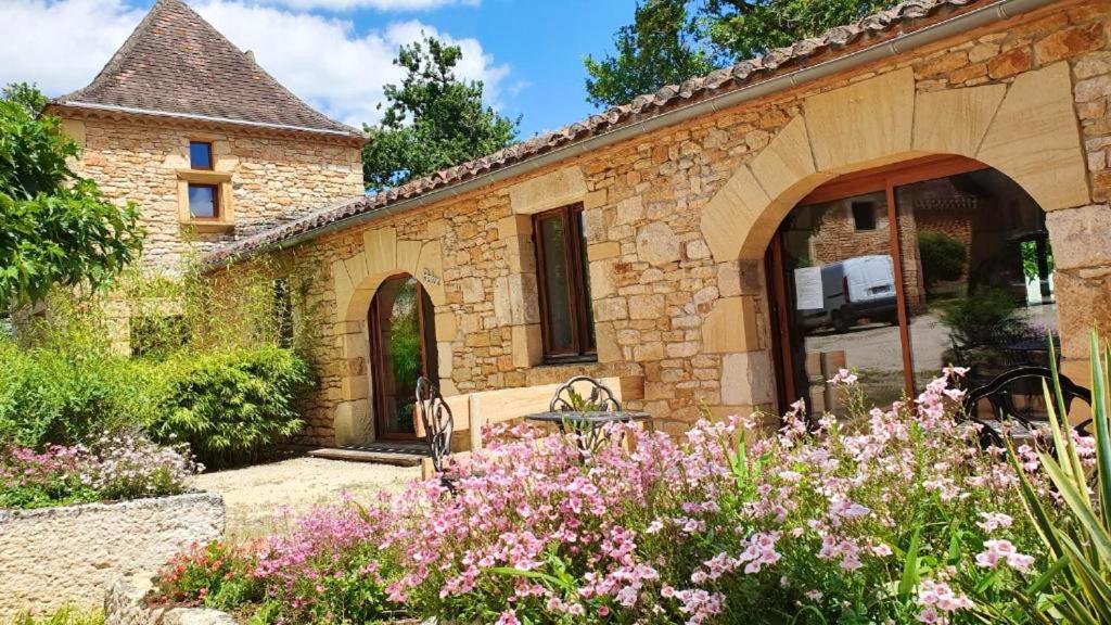 ein Steinhaus mit einem Garten mit Blumen in der Unterkunft Maison de 2 chambres avec piscine partagee jardin amenage et wifi a Puy l'Eveque in Puy-lʼÉvêque