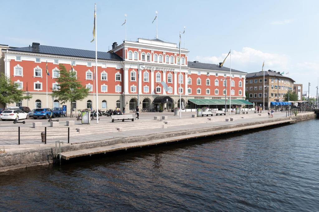 ein großes rotes Gebäude neben einem Fluss mit Gebäuden in der Unterkunft Elite Stora Hotellet in Jönköping