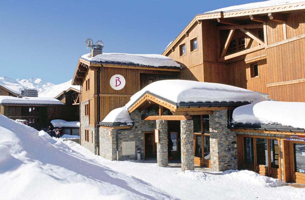 レ・メニュアールにあるBelambra Clubs Résidence Les Menuires - Le Hameau Des Airellesの屋根に雪を積んだスキー場