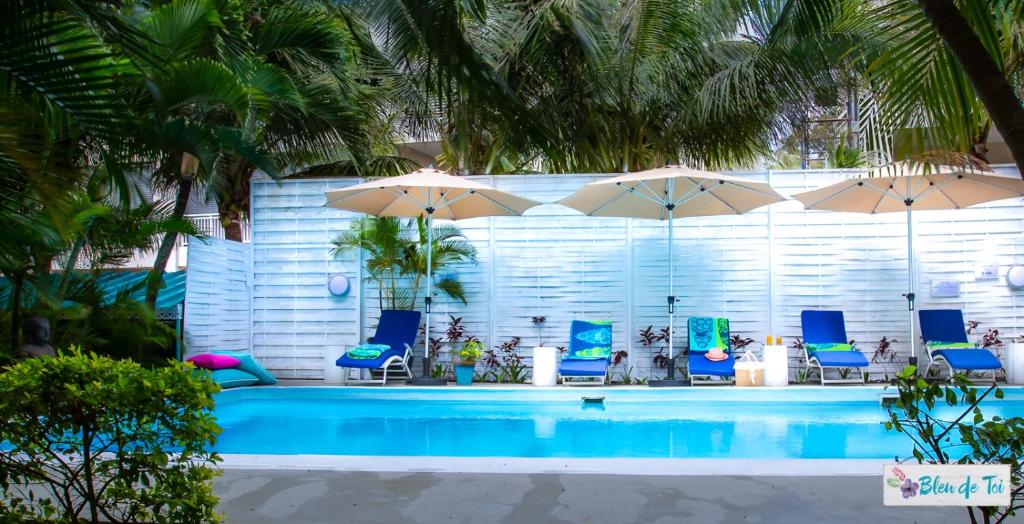 uma piscina com cadeiras azuis e guarda-sóis em Bleu de Toi Boutique Guesthouse em Pereybere