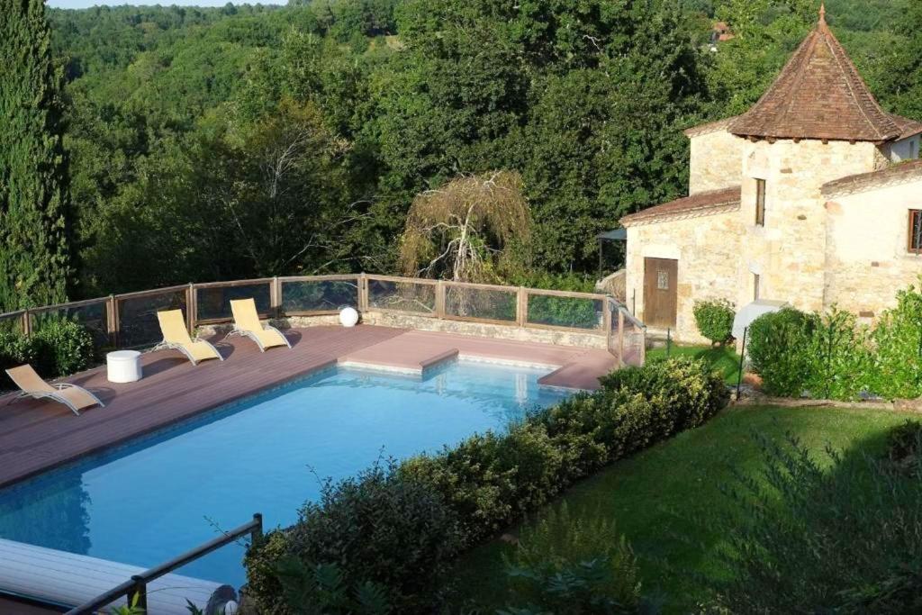 einen Pool mit Stühlen neben einem Gebäude in der Unterkunft Maison de charme à Puy-l'Évêque avec piscine partagée in Puy-lʼÉvêque