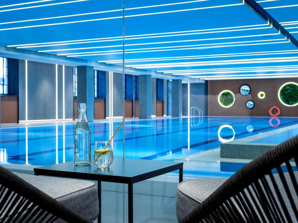a swimming pool with a table in front of a pool at Mercure Krakow Fabryczna City in Kraków