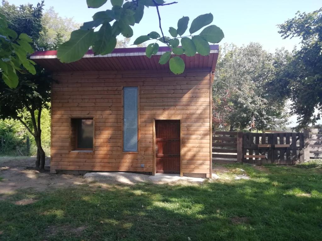 um pequeno edifício de madeira com uma porta na relva em Le Bellevue em Dolomieux