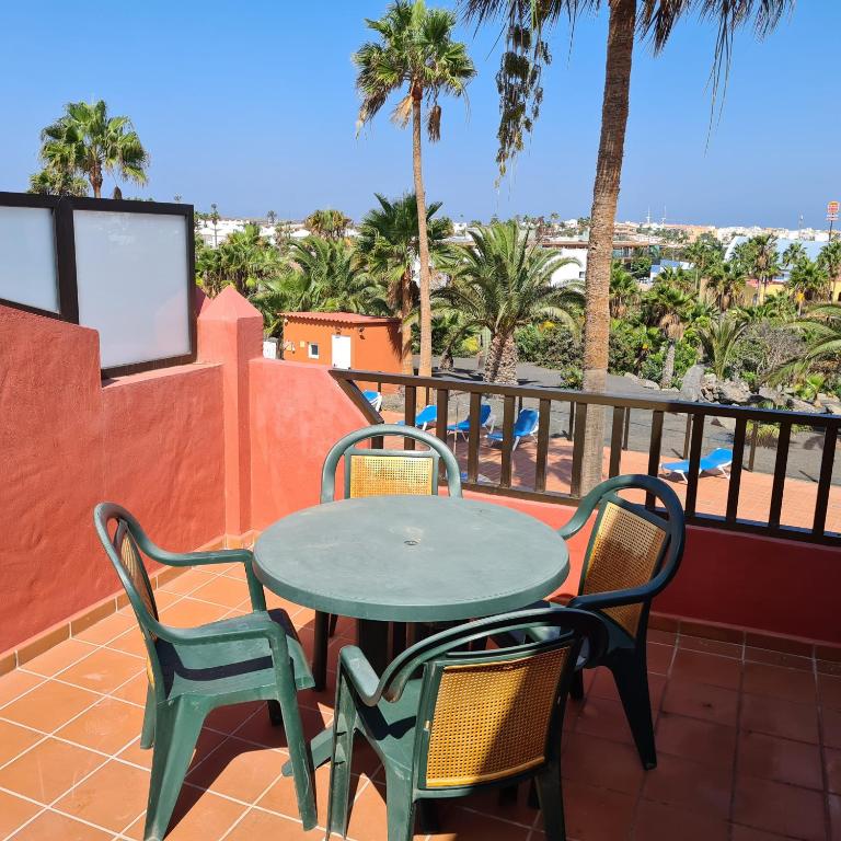 d'une table et de chaises sur un balcon avec des palmiers. dans l'établissement Oasis Royal D311, à Corralejo