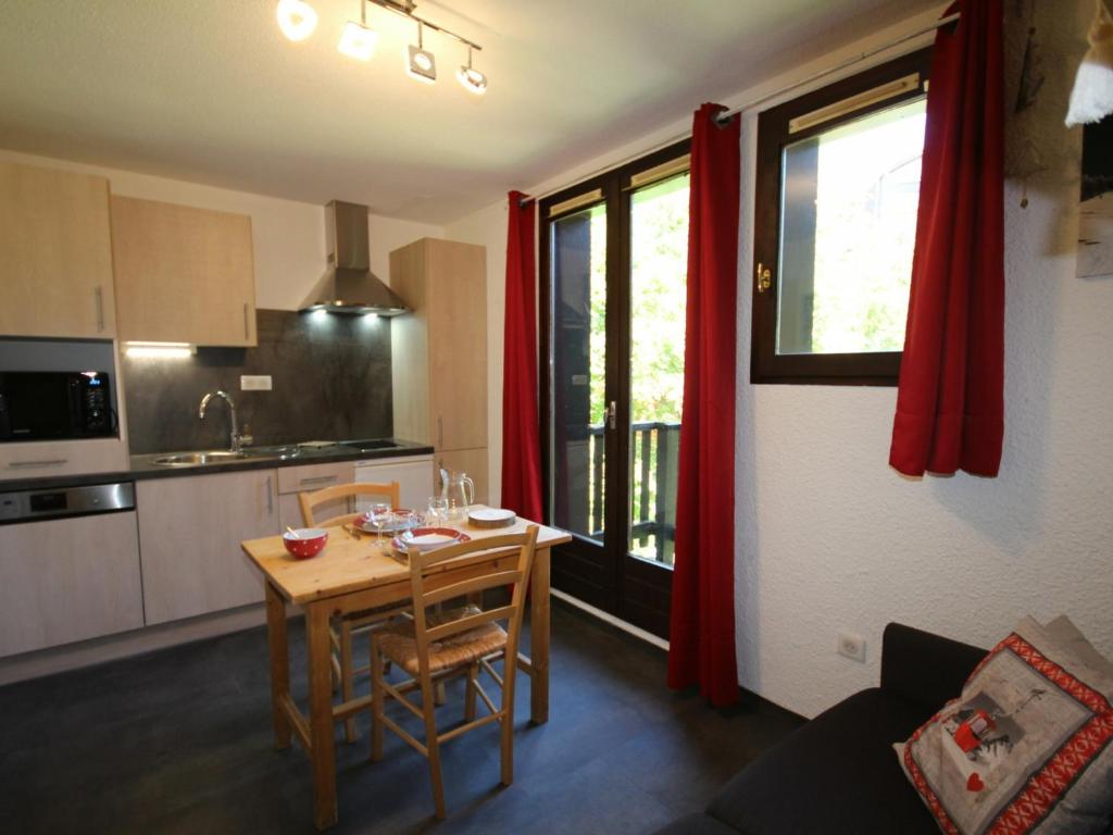 a kitchen with a small table and a kitchen with red curtains at Studio Les Saisies, 1 pièce, 2 personnes - FR-1-293-245 in Hauteluce