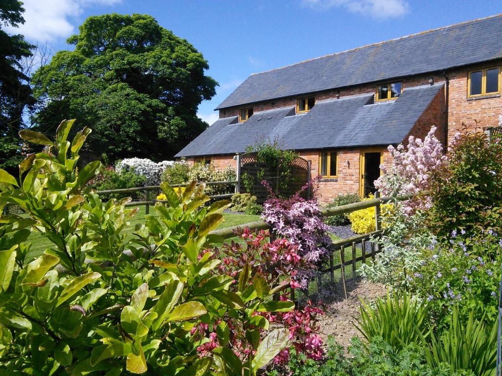 凱尼爾沃思的住宿－North Mere Rural Cottages，一座古老的砖房,前面有一个花园