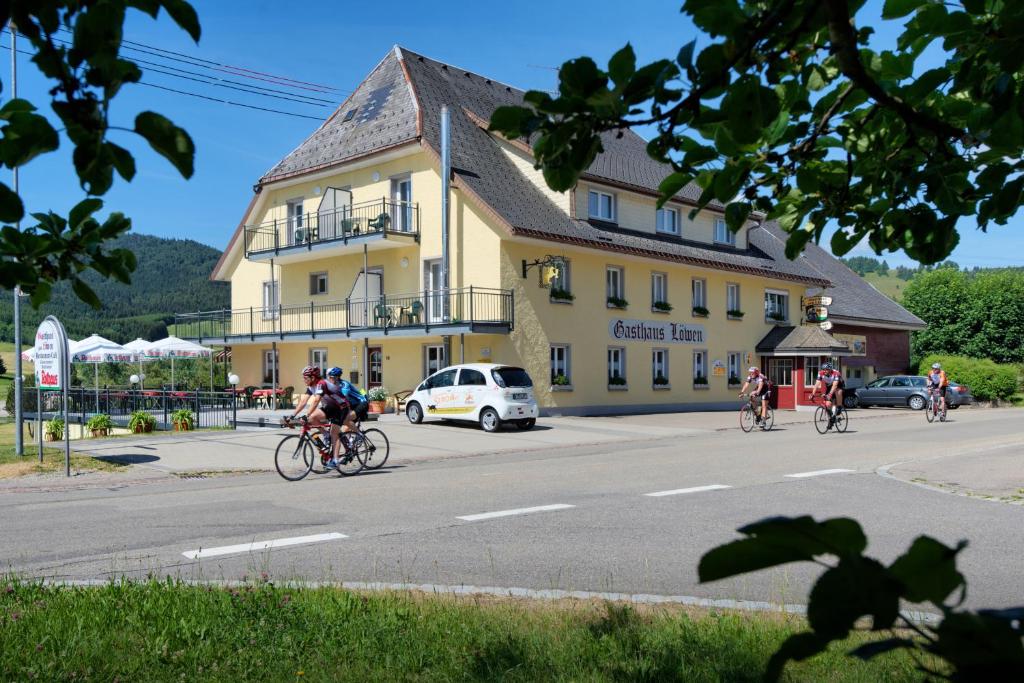 a group of people riding bikes down a street in front of a building at Landhotel Löwen Bernau in Bernau im Schwarzwald
