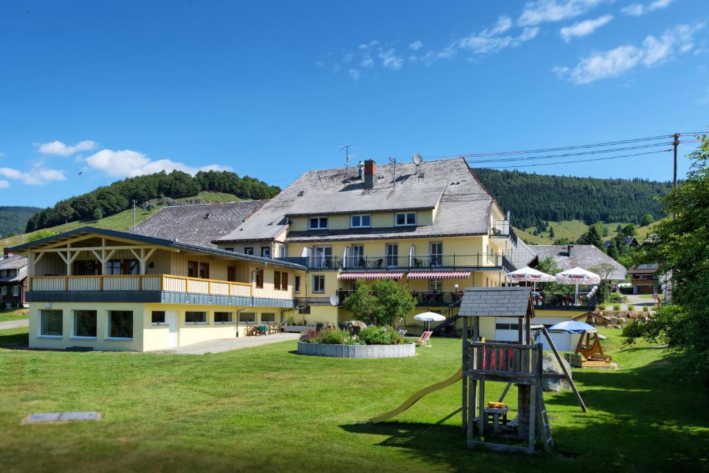 ein großes gelbes Gebäude mit einem Spielplatz davor in der Unterkunft Gasthaus Löwen in Bernau im Schwarzwald
