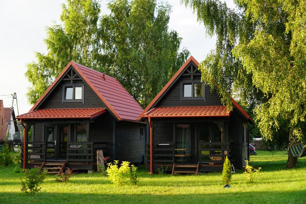 dom z czerwonym dachem na zielonym polu w obiekcie Mazurska Zagroda Domki Letniskowe w Rydzewie