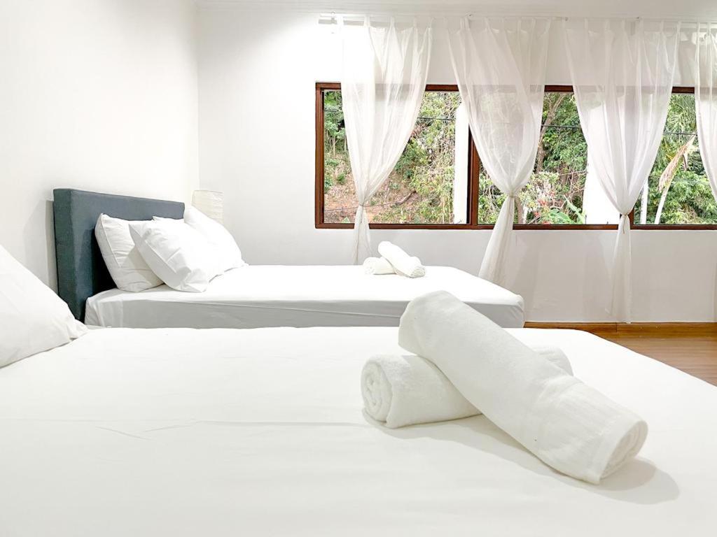 two white beds in a room with two windows at Mas Homestay in Kuala Lumpur