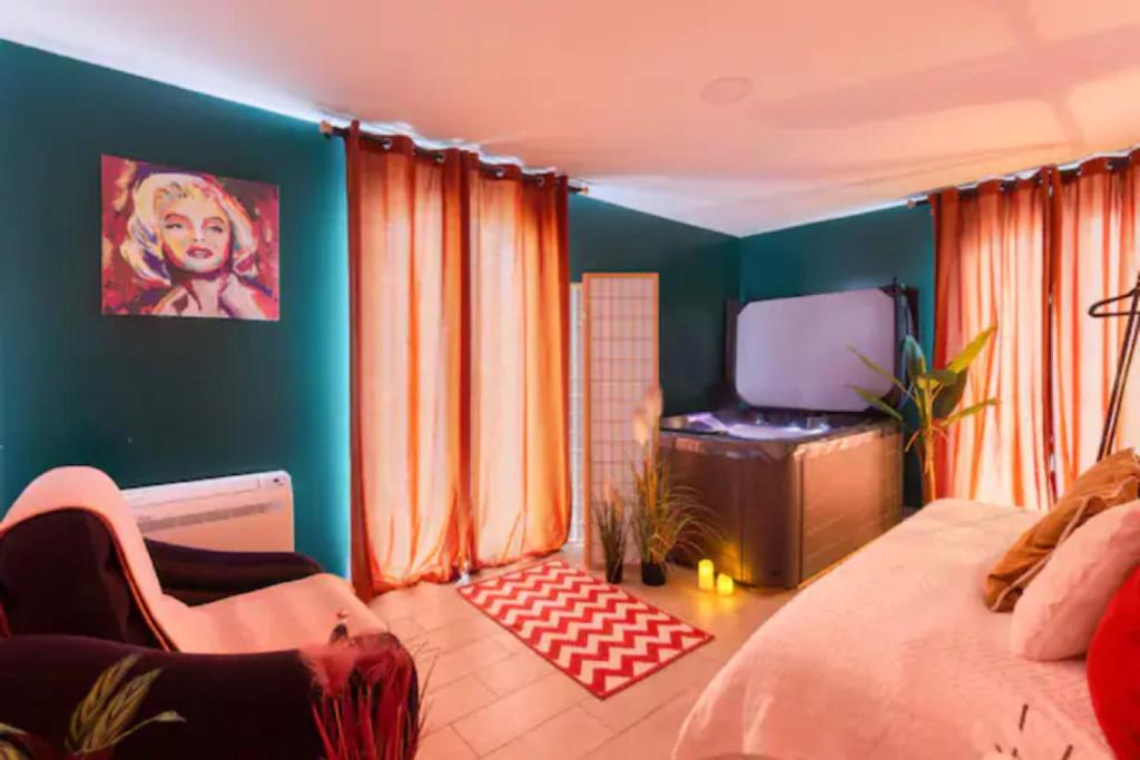 Schlafzimmer mit einem Bett und einem Flachbild-TV in der Unterkunft Suite Marilyn Monroe & SPA - 5P - Proche Disney in Montry