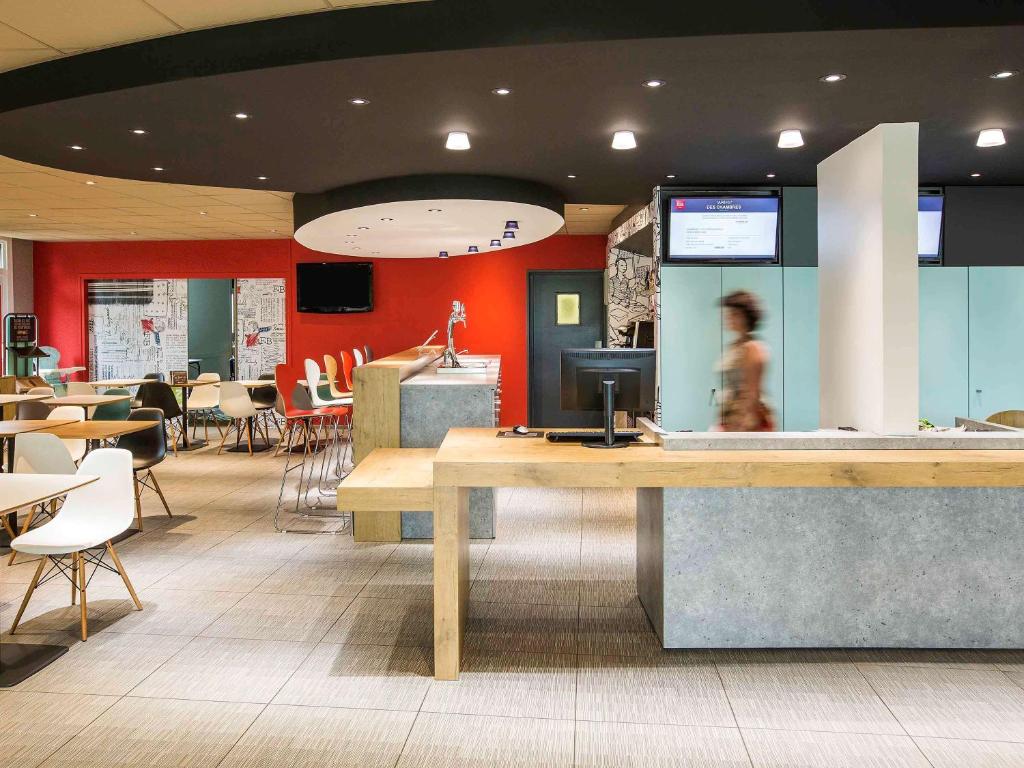 a restaurant with a counter and tables and chairs at ibis Rennes Cesson in Cesson-Sévigné