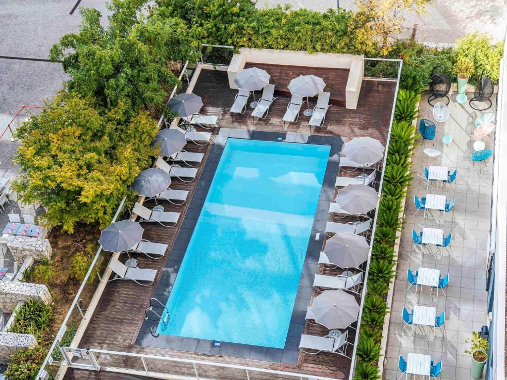 an overhead view of a swimming pool with chairs and umbrellas at ibis Styles Nice Aéroport Arenas in Nice