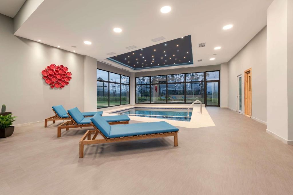 a pool room with blue chairs and a swimming pool at Wyndham Quito Airport in Tababela