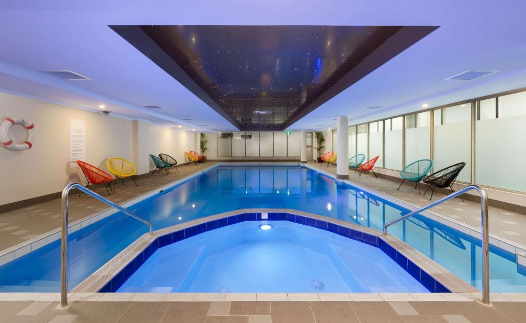 - une piscine dans un bâtiment avec des chaises dans l'établissement Rydges Sydney Central, à Sydney
